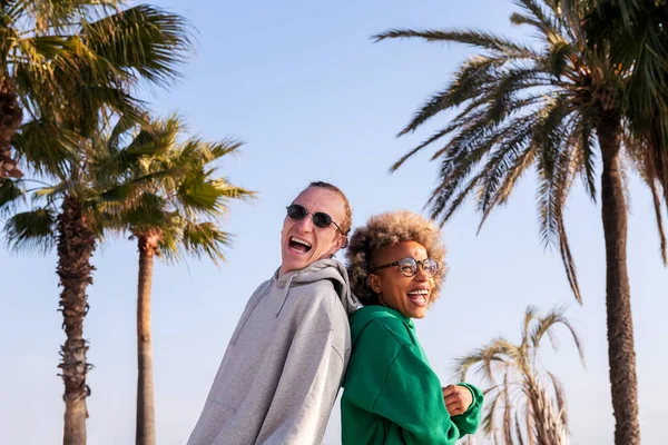 Sırt sırta verip gülen genç bir çift.