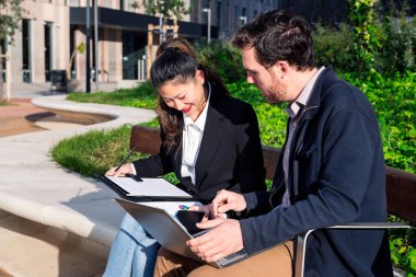 İş ortakları dışarıda dizüstü bilgisayarla çalışıyor.