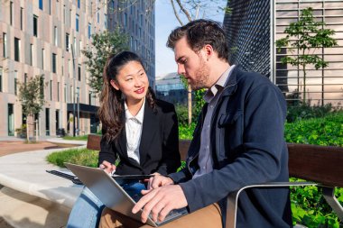 Kadın ve erkek parkta dizüstü bilgisayarla çalışıyor.