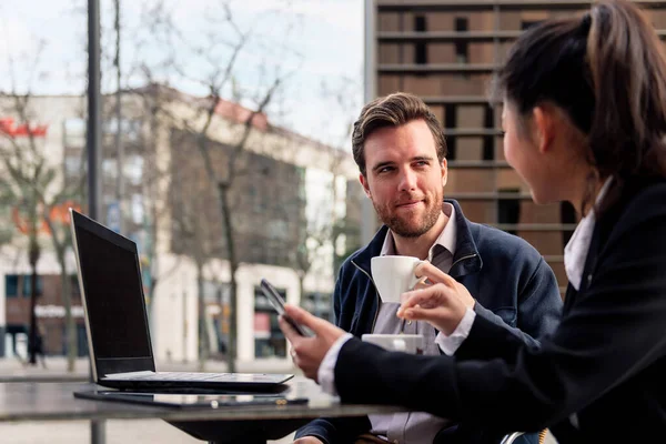 young businessman has a work meeting with his partner over coffee on a terrace in the financial district, concept of entrepreneurship and business, copy space for text