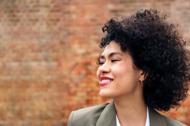 portrait of a young latin woman with curly hair smiling happy, concept of youth and happiness, copy space for text