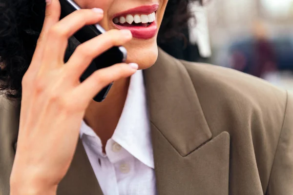 close up of the mouth of a smiling woman talking by mobile phone, concept of communication and urban lifestyle, copy space for text