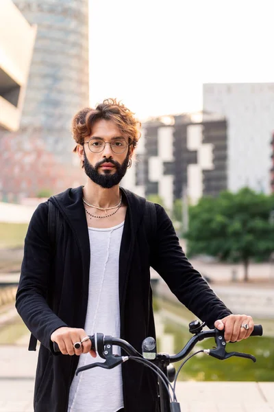 vertical portrait of a young caucasian man holding his bike in the city, concept of urban lifestyle and sustainable mobility, copy space for text