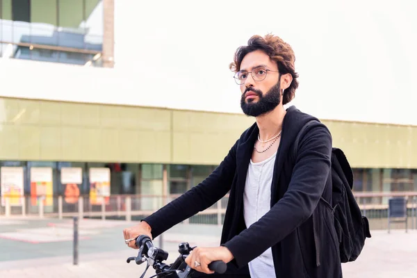 stylish caucasian man with beard riding around the city on his bike, concept of urban lifestyle and sustainable mobility, copy space for text