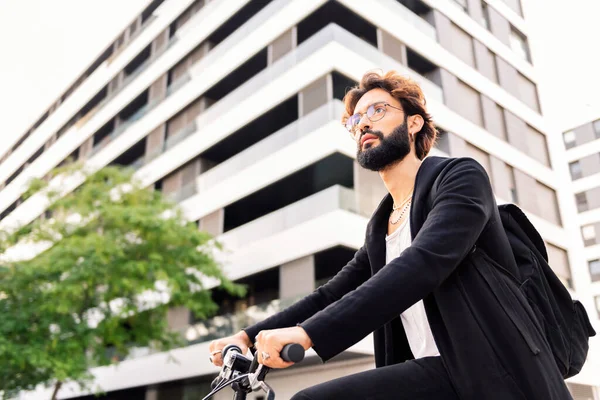 stylish young bearded man riding his bike through the city, concept of urban lifestyle and sustainable mobility, copy space for text
