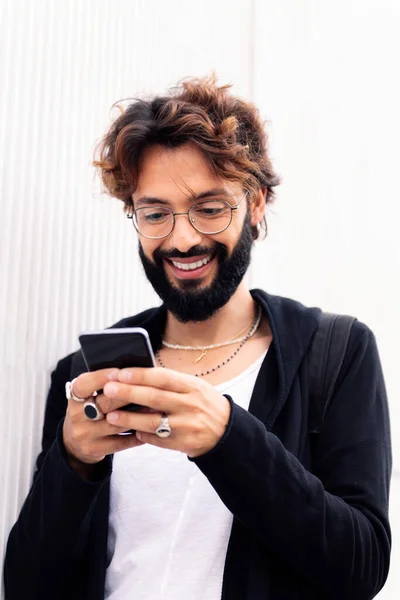Усміхнений Молодий Чоловік Бородою Білій Стіні Друкує Щасливий Мобільному Телефоні — стокове фото