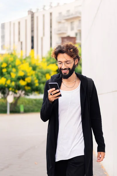 Uśmiechnięty Młody Człowiek Brodą Spacerujący Szczęśliwy Przez Miasto Pomocą Telefonu — Zdjęcie stockowe