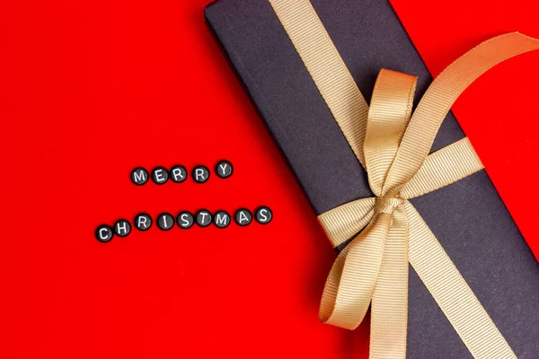 Um presente de Natal. Caixa de presente com fita bege. Feliz Natal, com letras. Caixa de presente preto. — Fotografia de Stock