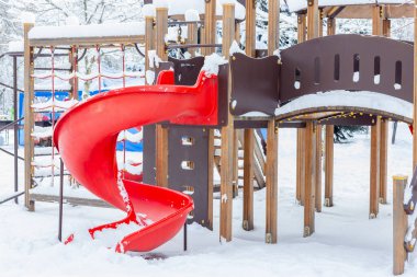 Oyun parkı karla kaplıydı. Çocuklar karın altında kayıyor..