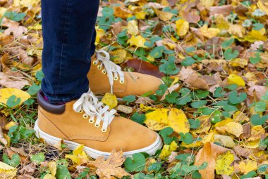 Çizmeli kadın bacakları. Sonbahar ormanında düşen yapraklar.