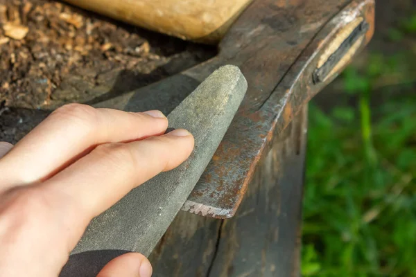 Manual sharpening of an axe. Grinding stone in the hands of the master. High quality photo