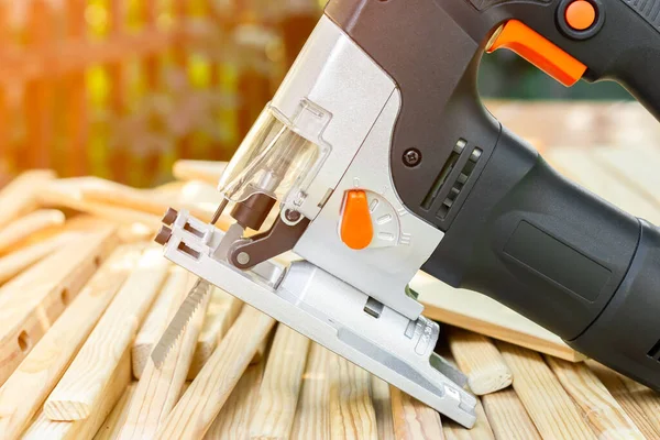 Electric jigsaw on a pile of wooden planks. Power tools for working with wood. High quality photo