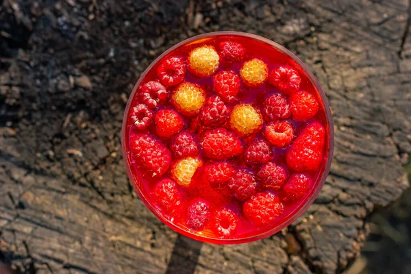 Raspberry jelly on a wooden background. Fruit jelly in sunlight. Sweet dessert. High quality photo