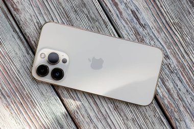UKRAINE, DNEPR - JULY 18, 2022: smartphone Apple Iphone 13 Pro on a light wooden table. Back view. High quality photo