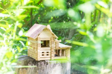 Toy wooden house in the sun. Model of a wooden house. Fairytale house on the background of nature. High quality photo