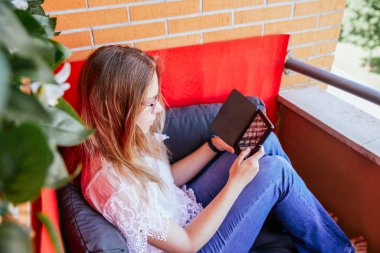 Evinin terasında kitap okuyan bir kızın en iyi görüntüsü..