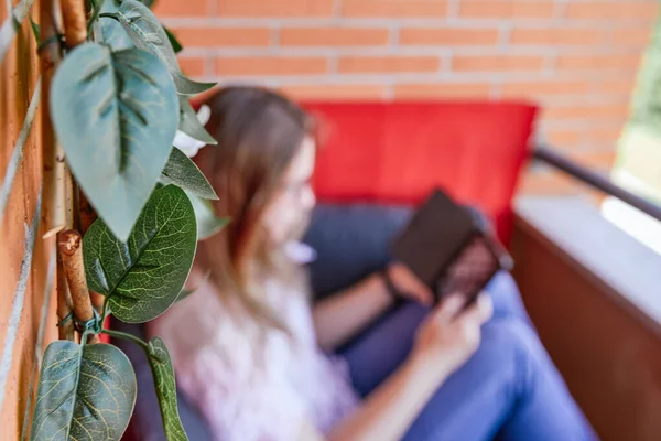 Ekolojik bitki örtüsü terasında kitap okuyan genç bir kadın var.