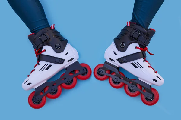 Two legs of a girl with inline skates facing each other on a blue background with copyspace