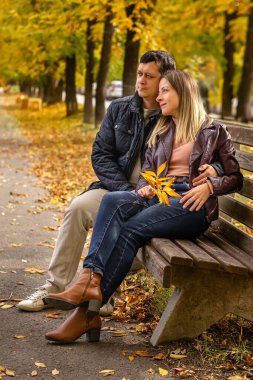 Aşık bir çift, sonbahar parkında bankta oturur..