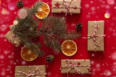 Kırmızı arka planda noel süslemeleri olan ladin dalının altında yeni yıl hediyelerinin yakın plan görüntüsü.