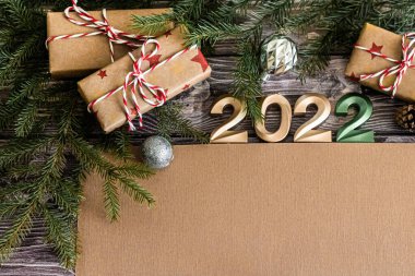 Koyu renk ahşap arka plandaki yeni yıl tebrik kartı 2022 numaralı bej yeri mesajınız için hediye ediyor..
