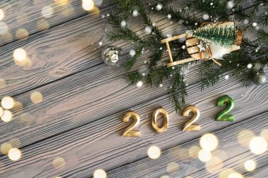 Yeni yıl kutlamalarının zamanı geldi. Hafif ahşap arka planda fotokopi alanı olan kartpostal, Noel oyuncak kızağı ve köknar dallı 2022 numara..