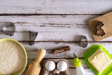 Fırıncılık için çeşitli malzemeler. Un, yumurta, tarçın, tereyağı, mutfak gereçleri ve mavi ahşap arka planda Paskalya kurabiyeleri için pişirme kabı. Yukarıdan bak. Boşluğu kopyala.