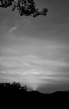 Klasik günbatımı manzarası dağda akşam, ağaçların silueti bir orman ve turuncu gökyüzünde, gri bulutlar, dikey resim konsepti.