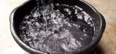 Büyük siyah bir kase üzerinde bitmek bilmeyen yağmur damlaları, kırsal alanda yüzeyde yağmurlu bir gün konseptine çarptıktan kısa bir süre sonra tekrar havaya sıçrar..