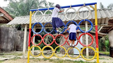 Oyun parkında renkli lastik tekerleklerin üzerinde duran Asyalı bir kızın görüntüsüyle. Kırsal bölgelerde Taylandlı öğrenciler.
