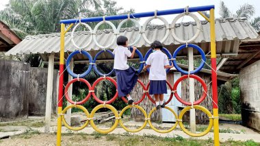 Oyun parkında renkli lastik tekerleklerin üzerinde duran Asyalı bir kızın görüntüsüyle. Kırsal bölgelerde Taylandlı öğrenciler.