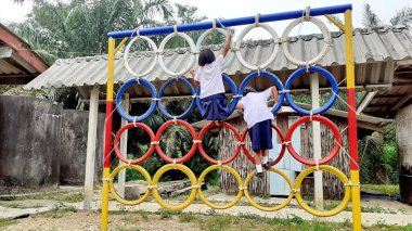 Oyun parkında renkli lastik tekerleklerin üzerinde duran Asyalı bir kızın görüntüsüyle. Kırsal bölgelerde Taylandlı öğrenciler.