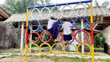 Oyun parkında renkli lastik tekerleklerin üzerinde duran Asyalı bir kızın görüntüsüyle. Kırsal bölgelerde Taylandlı öğrenciler.