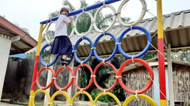 Oyun parkında renkli lastik tekerleklerin üzerinde duran Asyalı bir kızın görüntüsüyle. Kırsal bölgelerde Taylandlı öğrenciler.