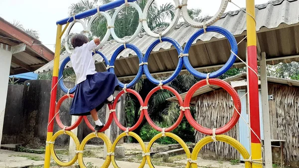 Oyun parkında renkli lastik tekerleklerin üzerinde duran Asyalı bir kızın görüntüsüyle. Kırsal bölgelerde Taylandlı öğrenciler.