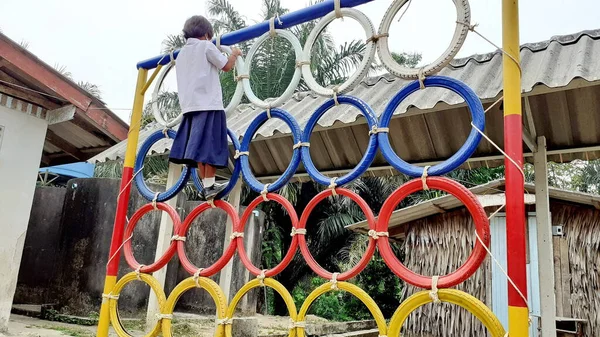 Oyun parkında renkli lastik tekerleklerin üzerinde duran Asyalı bir kızın görüntüsüyle. Kırsal bölgelerde Taylandlı öğrenciler.