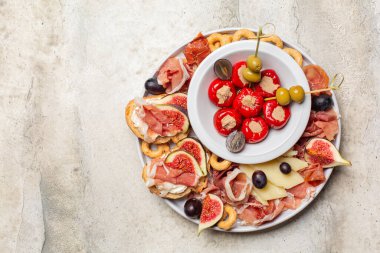 Aperatifler. Brüksel usulü jambon, Parma peyniri, ton balığı, dolgulu mini dolma biber, taralli, zeytin, üzüm ve incir. Geleneksel İtalyan aperatifi. Boşluğu kopyala.