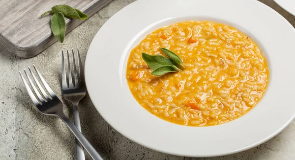 Balkabağı ve taleggio peynirli risotto yakın plan, adaçayı yapraklarıyla süslenmiş. Sancak boyutu.