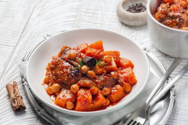 Balkabağı, kuzu eti ve tarçın çubuklu nohut güveci. Whie ahşap masa.