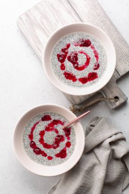 Hindistan cevizi sütü ve taze kızılcık soslu Chia pudingi. Dikey resim.