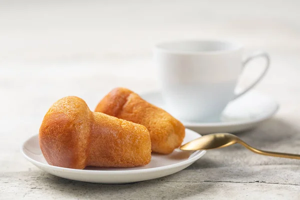 Rum baba ya da baba au rhum. Romlu şurupla doldurulmuş küçük maya keki. Yakın plan, seçici odaklanma. Kahve fincanı. Hafif arkaplan.
