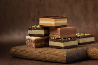 İtalyan kreminosu - tipik çikolata şekli Piedmont kökenli, farklı katmanlardan oluşmuş, Gianduja çikolatası, kahve, pistacchio veya fındık ezmesinden yapılmış bir küp. Kahverengi arkaplanda.