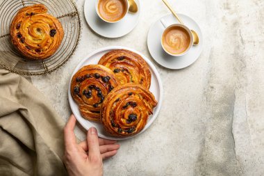 Preparing french or continental breakfast with espresso coffee and croissant. Pain aux raisins, also called escargot or pain russe, is a spiral pastry with custard cream and raisin.