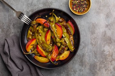 Izgara şeftali ve yeşil dolmalık salata ile bal ve siyah, kırmızı ve beyaz biber. Gri tablo yüzeyi.