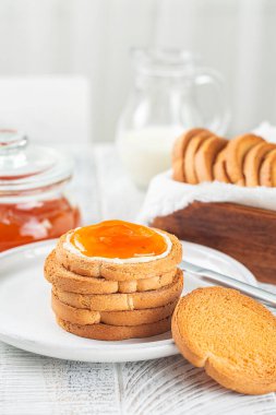 Avrupai İtalyan Kahvaltısı. Kayısı reçeli ve tereyağlı Rusks veya Fette Biscottate veya Zwieback, kızarmış ekmek. Süt. Beyaz masa. Dikey resim.