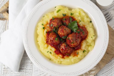 Domates soslu ev yapımı köfteler ve beyaz tabakta patates püresi. Üst görünüm.