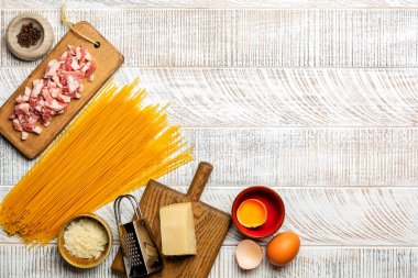 Geleneksel İtalyan makarna carbonara, spagetti, pancetta, yumurta sarısı, karabiber ve beyaz ahşap yüzeyde parmesan peyniri. Boşluğu kopyala.