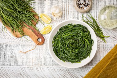Limonlu Sauteed Agretti 'nin en iyi manzarası, İtalyan yemekleri. Çiğ malzeme. Tuzlu ya da salsola soda. Beyaz tablo.