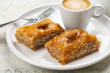 Baklava ve espresso kahvesi. Filo pastasından yapılmış, doğranmış badem fıstığı ile doldurulmuş ve şurup veya bal ile tatlandırılmış hamur tatlısı. Orta Doğu ve Akdeniz tatlı yiyecekleri. Ev yapımı. Yakın çekim..