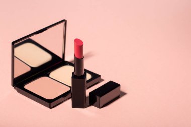 Açık şeftali rengi arka planda dekoratif kozmetik seti. Ruj ve yüz pudrası..